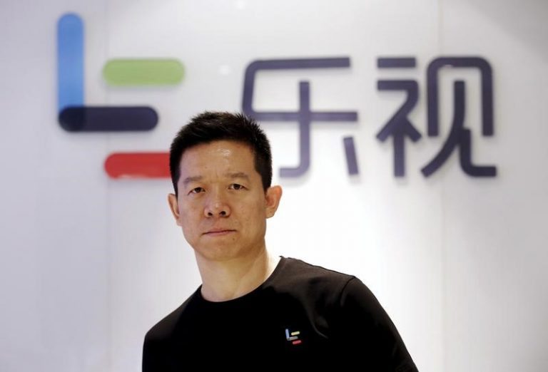 Jia Yueting, co-founder and head of Le Holdings Co Ltd, poses for a photo in front of a logo of his company in Beijing