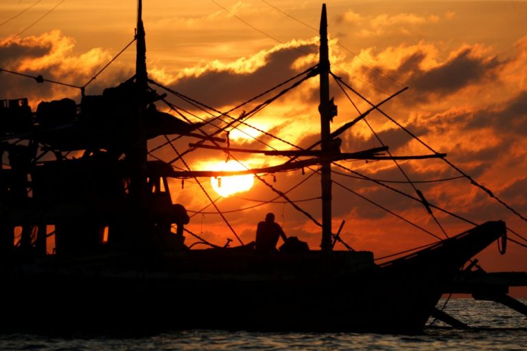 A Philippine fisherman sits on his boat during sunset at the disputed Scarborough Shoal
