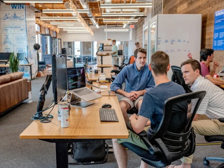Three men discussing account planning for Salesforce at a table in a professional office environment.